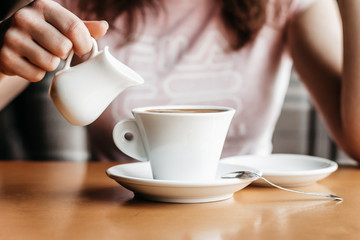 Morning coffee. Closeup of women's hands with coffee cup in a cafe. Female hands holding cups of coffee on a wooden table background in a cafe, vintage color tone