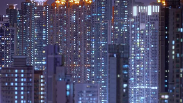Loop of Hong Kong apartments at night. Chinese crowded city with lights turning on and off at midnight. Fast paced modern Asian night-scape time lapse in urban metropolis.