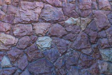 Contrast photo of a fragment of a wall made from raw rough varnished stone