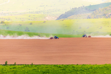 Obraz premium Dust from a tractor working in a field in spring