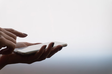 Female hands holding a smartphone on light gradient background