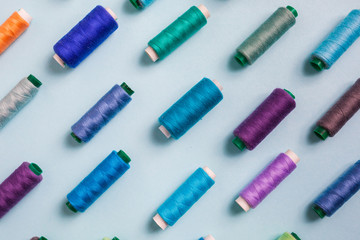 Flat lay composition with sewing threads on blue background