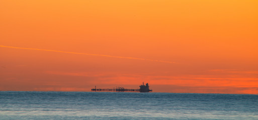 Fototapeta premium Freighter sailing at dawn