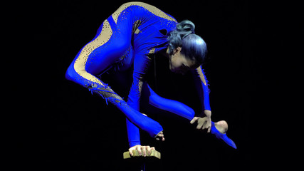 Fototapeta na wymiar Flexible beautiful slim gymnast artist performing on the stage.
