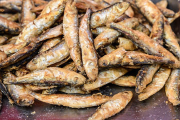Close up of a portion of deep fried anchovies ready to eat on a metallic surface
