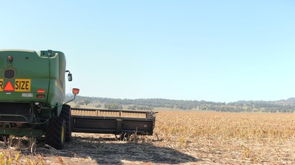 large green wheat grain combine harvester parked on a freshly harvested large wheat grain field on a farm in rural New South Wales, Australia