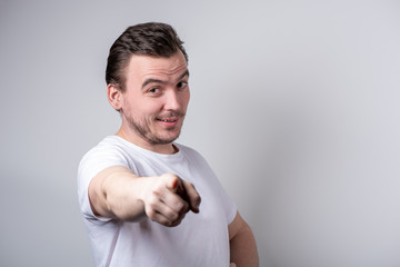 Handsome guy with bristles in a white T-shirt makes funny grimaces on his face