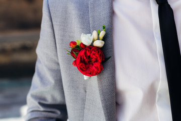 close-up of a boutonniere on a jacket. red rose
