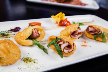 Mousse of cheese with bacon in eclair, covered with green and tomato cherry