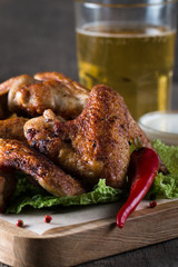 Close-up photo of bbq chicken wings with fries and beer. Barbeques meat with sauces, ketchup, mayonnaise. Fast and junk food concept. 