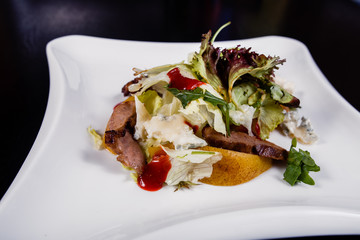 Appetizing salad sliced with pear slices of prosciutto pear arugula and parmesan