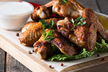 Close-up photo of bbq chicken wings with fries and beer. Barbeques meat with sauces, ketchup, mayonnaise. Fast and junk food concept. 