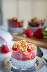 Chia pudding with strawberries walnuts and honey. Blurred background. White and red napkins 