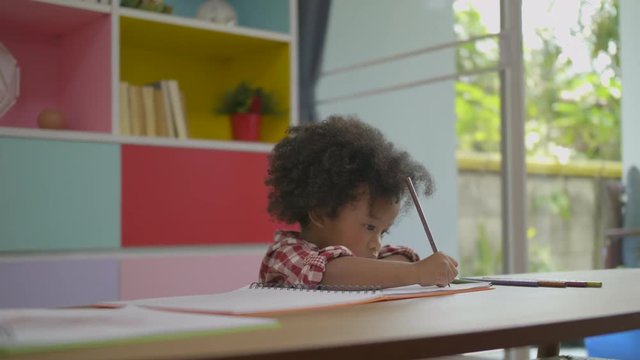 African ethnicity Child using pencil to practice drawing or writing on a book