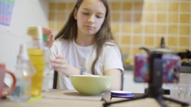 teen girl making fluffy slime at home on the kitchen