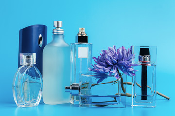 Perfume bottles with flowers on a light blue background