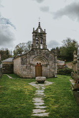 Small romanesque church and cemetery with a green courtyard in Galicia, Spain.