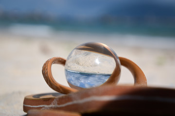 crystal ball lying in flip flop in beach sand