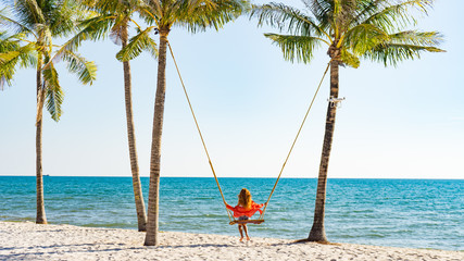 Vacation concept. Young woman swing on a beach swing. Happy traveller women on the Phu Quoc beach