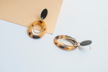 Earrings with leopard print on beige and brown color background with copyspace. Trendy jewellery.