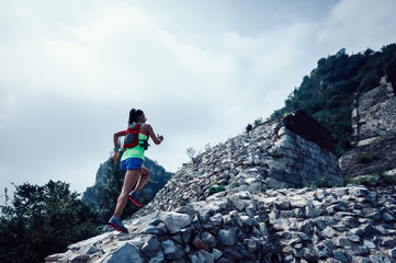 Fototapeta premium Fitness woman trail runner running at great wall on the top of mountain