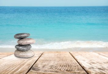 Stacked zen stones on wooden pier against sea, space for text