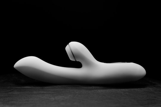 White vibrator on black skin. Dark background.