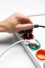Man inserting power plug into extension cord on white background, closeup. Electrician's professional equipment