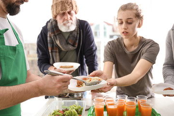 Volunteer giving food to poor people indoors