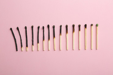 Row of burnt matches and whole one on color background, flat lay. Human life phases concept