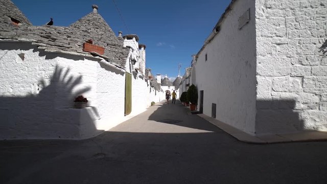 Tourists couple visiting typical town of Alberobello in Apulia region with trulli typical buildings unique in the world. Tourist running and jumping in the street
