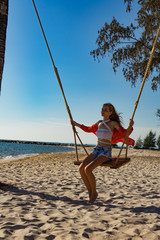 Vacation concept. Young woman swing on a beach swing. Happy traveller women on the Phu Quoc beach