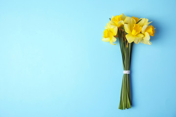 Bouquet of daffodils on color background, top view with space for text. Fresh spring flowers