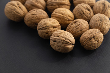 Walnuts in shell lying on black surface, side view. Healthy nuts and seeds background.
