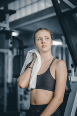 Young attractive woman caucasian sitting and using towel to wipe the sweat. Relaxation after hard workout in gym. Fitness concept, Healthy, Sport, Lifestyle