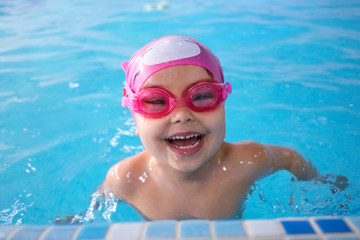 Fototapeta na wymiar Happy child in the swimming pool. Before swimming lessons Beautiful girl smiling in the pool before swimming in the competition