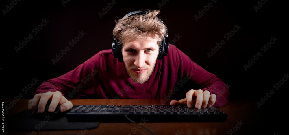 Wall mural young male playing computer video games on a table in a dark room b