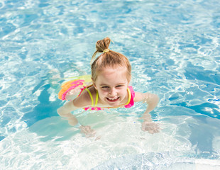 Fototapeta na wymiar Smiling girl swim to the poolside