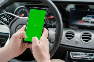 Man using smartphone on the background of a luxury class car dashboard