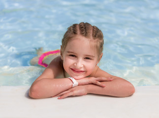 Fototapeta na wymiar Smiling girl swim to the poolside