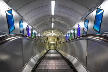 Rolltreppe nach unten im metallischen Tunnel
