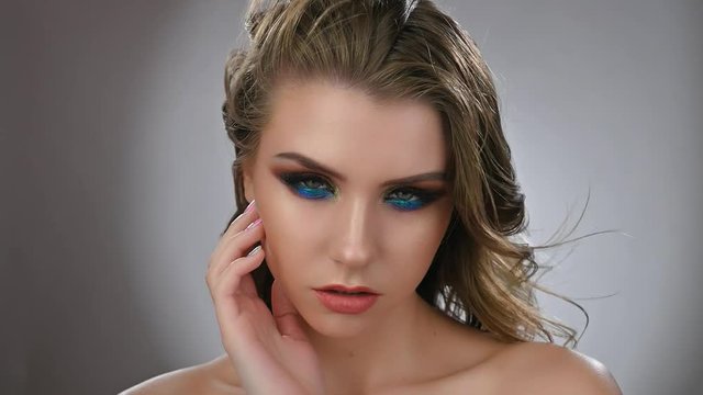 Fashion model young woman in trendy make-up posing in studio. Eye models with colorful glitter on the eyelids. Slow motion