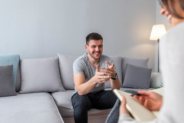 Psychologist talking with happy man in the office. Image of young man during psychological therapy....