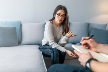 Obraz premium Woman at therapy session. Attentive psychologist. Attentive psychologist holding pencil in his hands making written notes while listening to his client