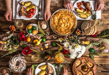Naklejka na ściany i meble Holiday friends or family at the holiday table with rabbit meat, vegetables, pies, eggs, top view.