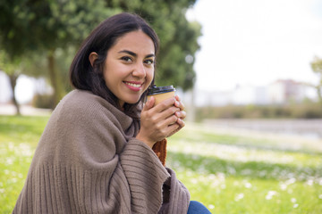 Positive pretty girl feeling cold and drinking hot coffee