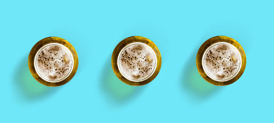Three glass of cold beer and chips on a blue background. Top view. Copy space. Cold summer drinks.