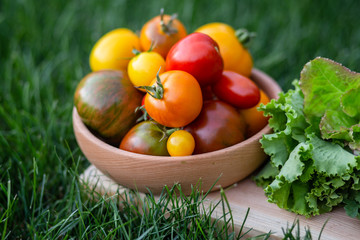 Lettuce, arugula leaves, tomatoes on a wooden plate