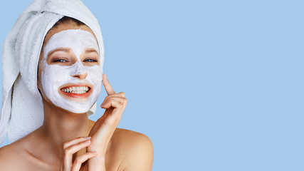 Beautiful young woman applying facial mask on her face. Skin care and treatment, spa, natural...