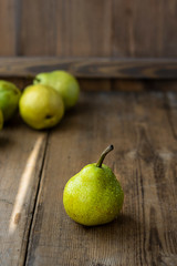 one fresh ripe organic yellow pear on rustic wooden brown table with defocused pears on background. Selective focus. Vertical with copy space. For design about agricilture, fruit and healthy food